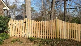 Image of a picket style fence. This fence has pointed vertical boards spaced two to three inches apart.