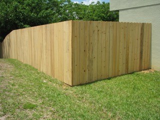 This is another image of a stockade fence. This is a tall, closed fence with vertical boards that are straight on their tops.