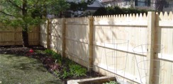 Image of a stockade style fence.  This is a tall closed fence with pointed vertical boards.
